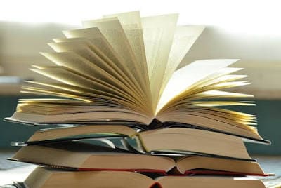 A stack of books with one open, pages fanning out.